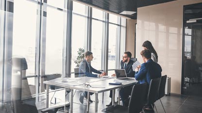 Un groupe d'hommes et de femmes en tenue de travail ayant une réunion dans une salle de conférence.