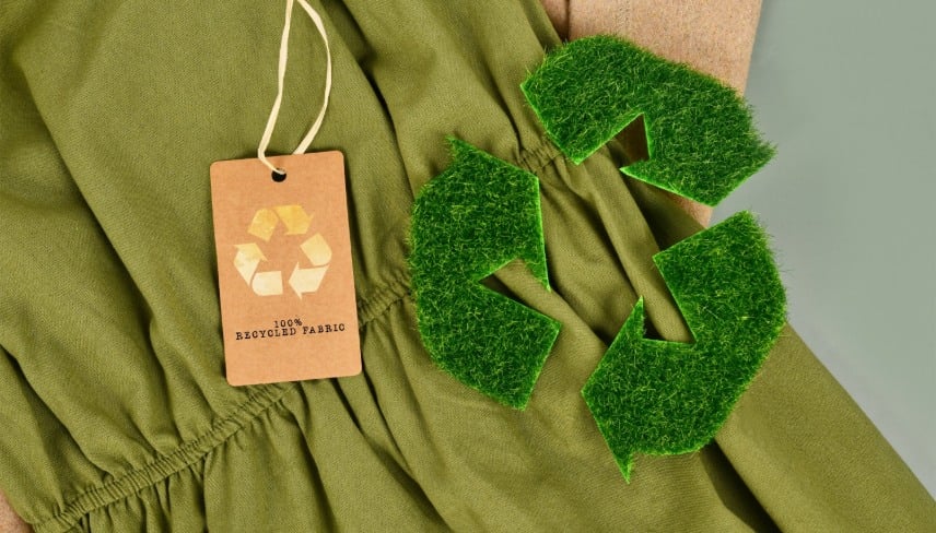 Photo d'un vêtement de couleur verte avec une étiquette en carton portant le symbole "recyclable".