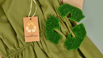 Photo d'un vêtement de couleur verte avec une étiquette en carton portant le symbole "recyclable".