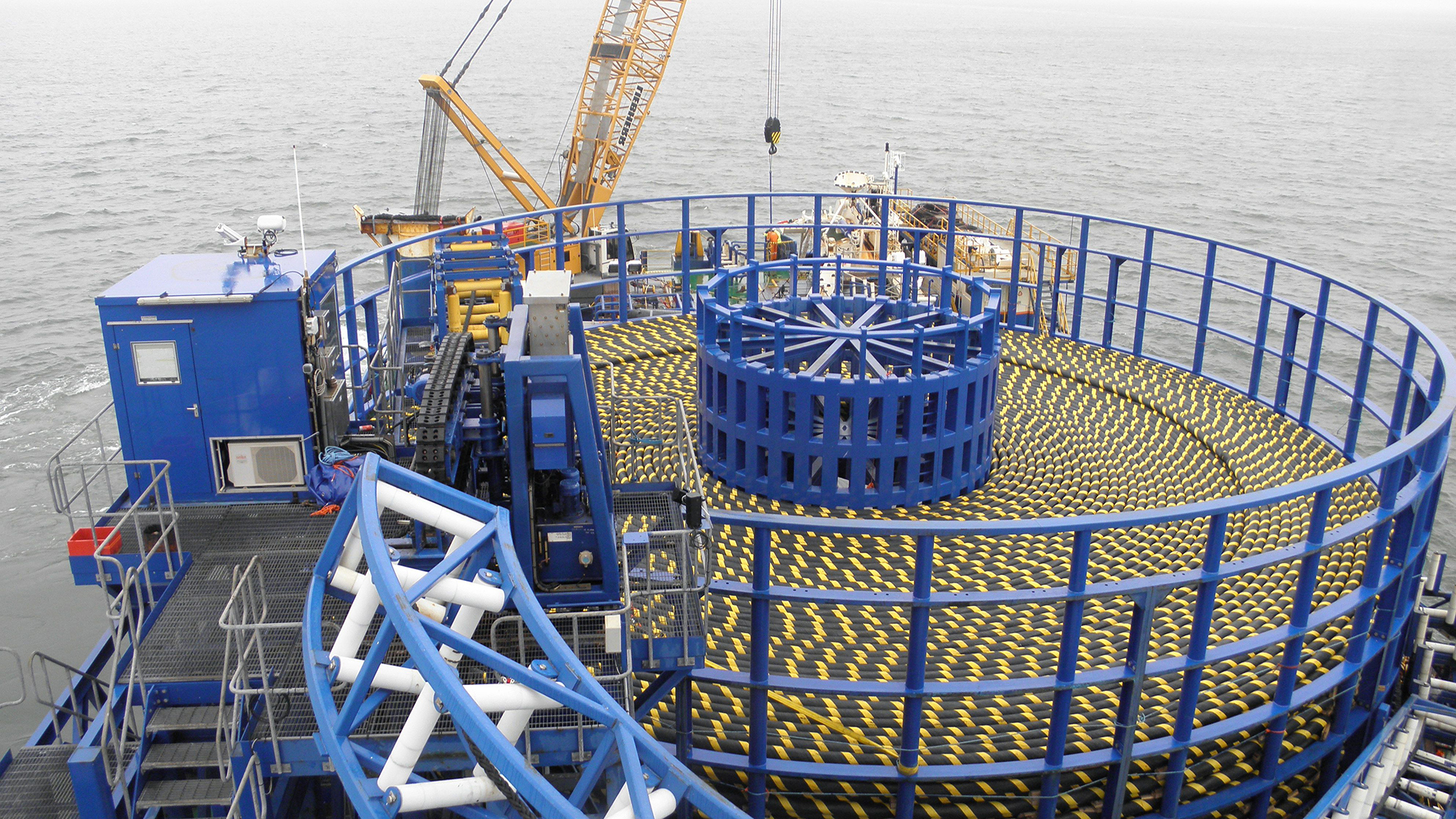 large spool of yellow industrial cables mounted on a ship in the water